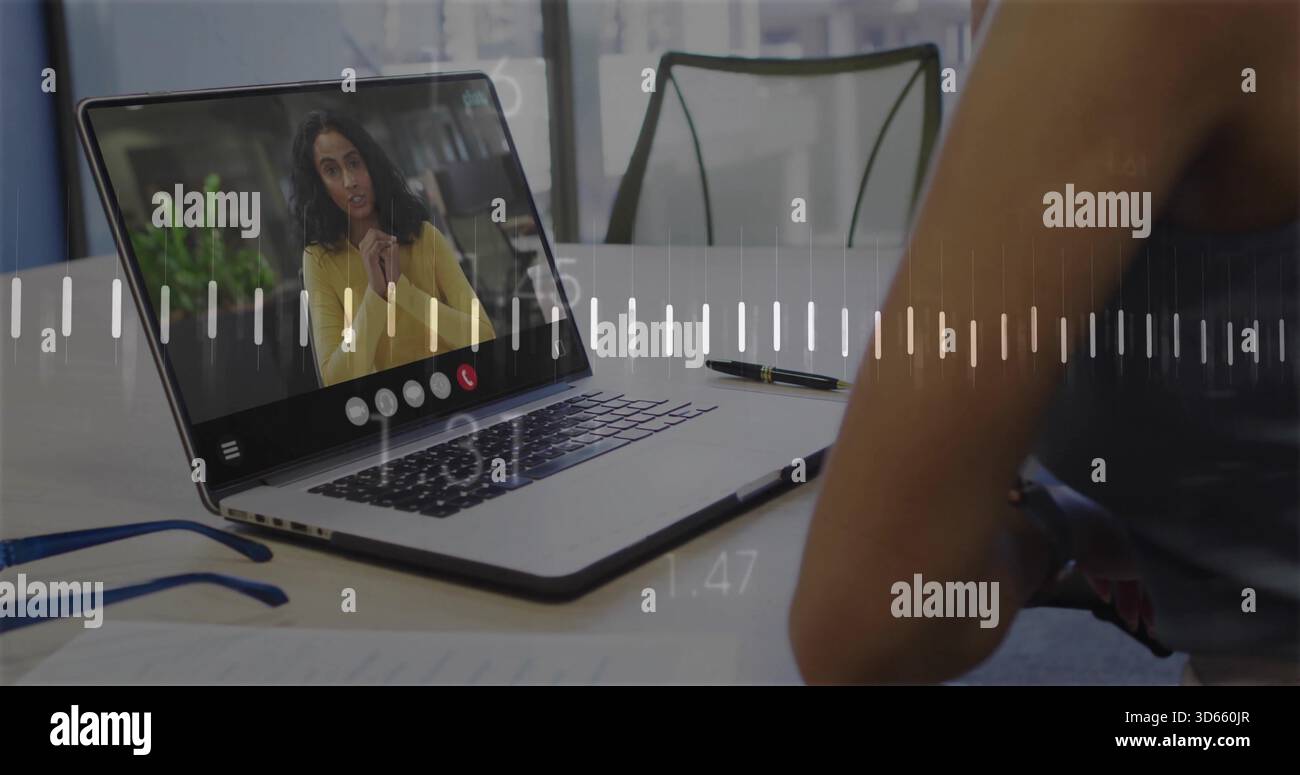 Mostra un laptop con donna remota che indossa il top della mostarda al tavolo, con occhiali blu e documenti Foto Stock
