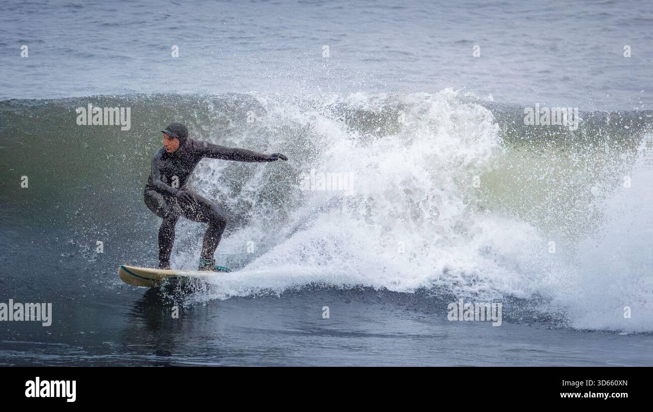 Druridge Bay, Northumberland 18 ottobre 2025 - coppia di surfisti, surf nella Baia di Druridge durante un'ondata autunnale. Foto Stock