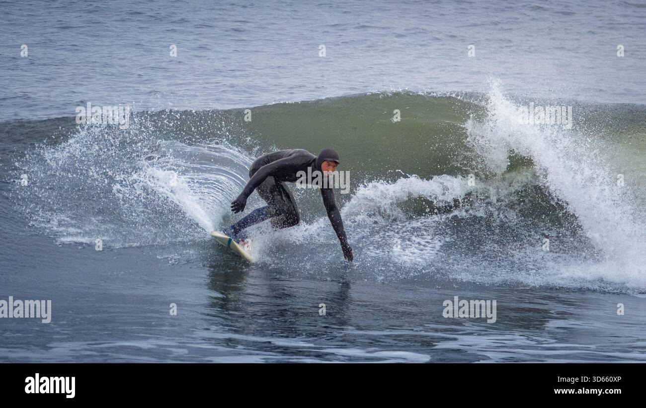 Druridge Bay, Northumberland 18 ottobre 2025 - coppia di surfisti, surf nella Baia di Druridge durante un'ondata autunnale. Foto Stock