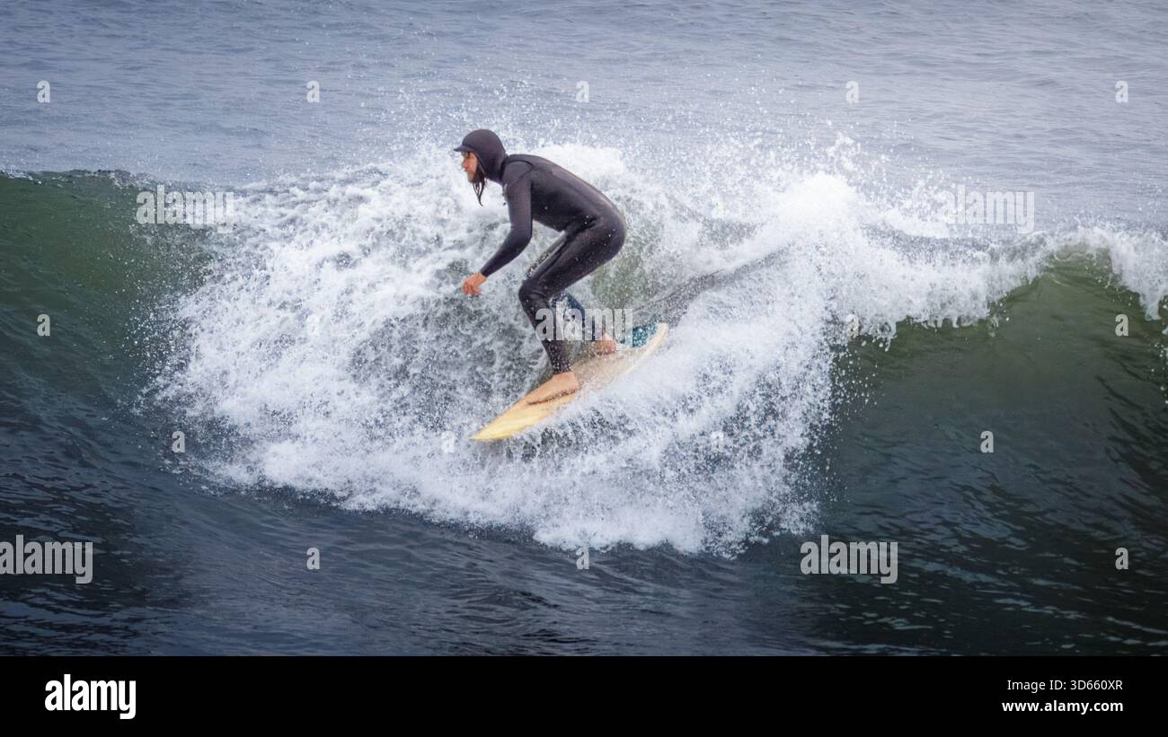 Druridge Bay, Northumberland 18 ottobre 2025 - coppia di surfisti, surf nella Baia di Druridge durante un'ondata autunnale. Foto Stock