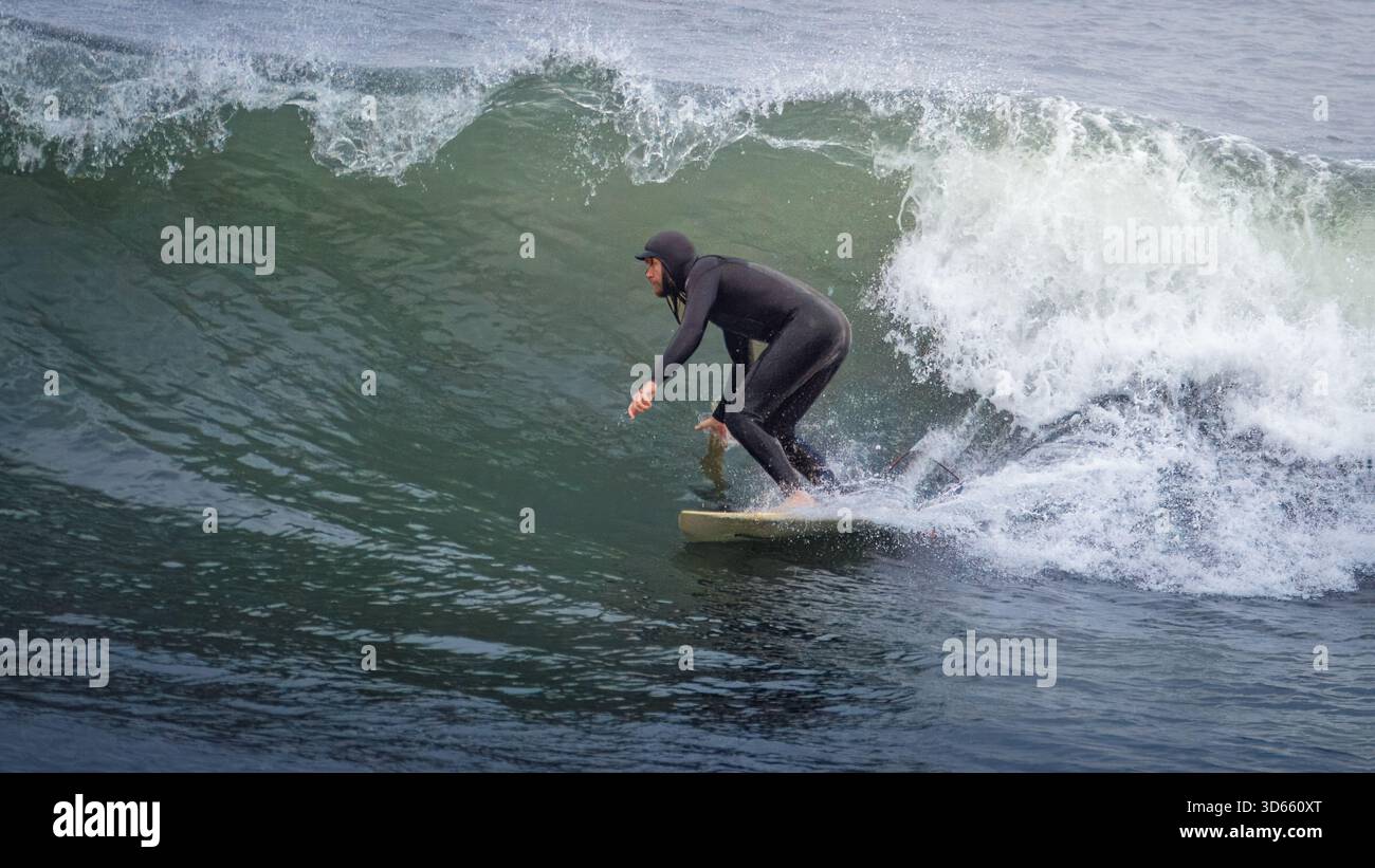 Druridge Bay, Northumberland 18 ottobre 2025 - coppia di surfisti, surf nella Baia di Druridge durante un'ondata autunnale. Foto Stock