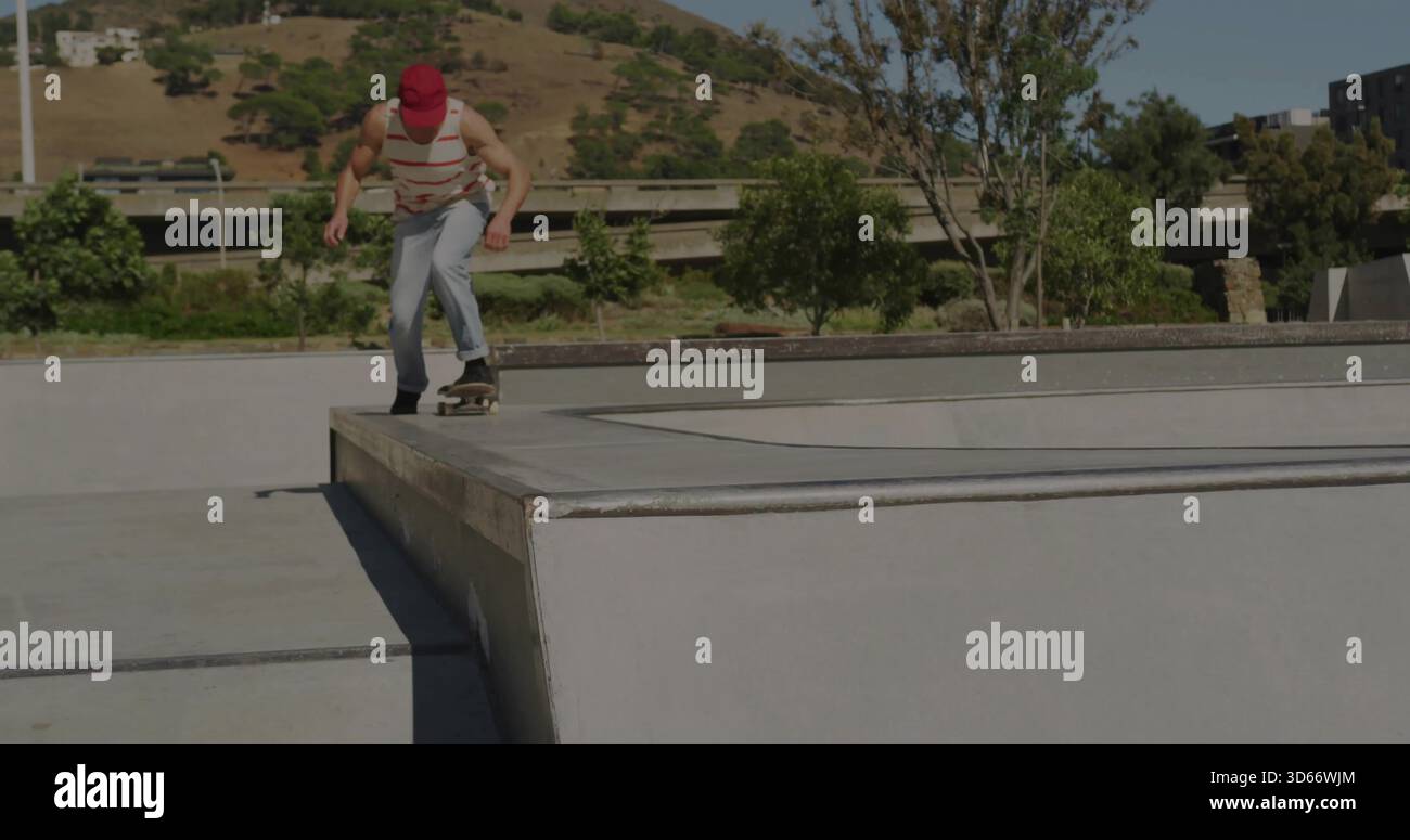 Skateboarder pendente che scende dalla sporgenza dello skatepark in berretto rosso con skateboard, spazio fotocopie Foto Stock