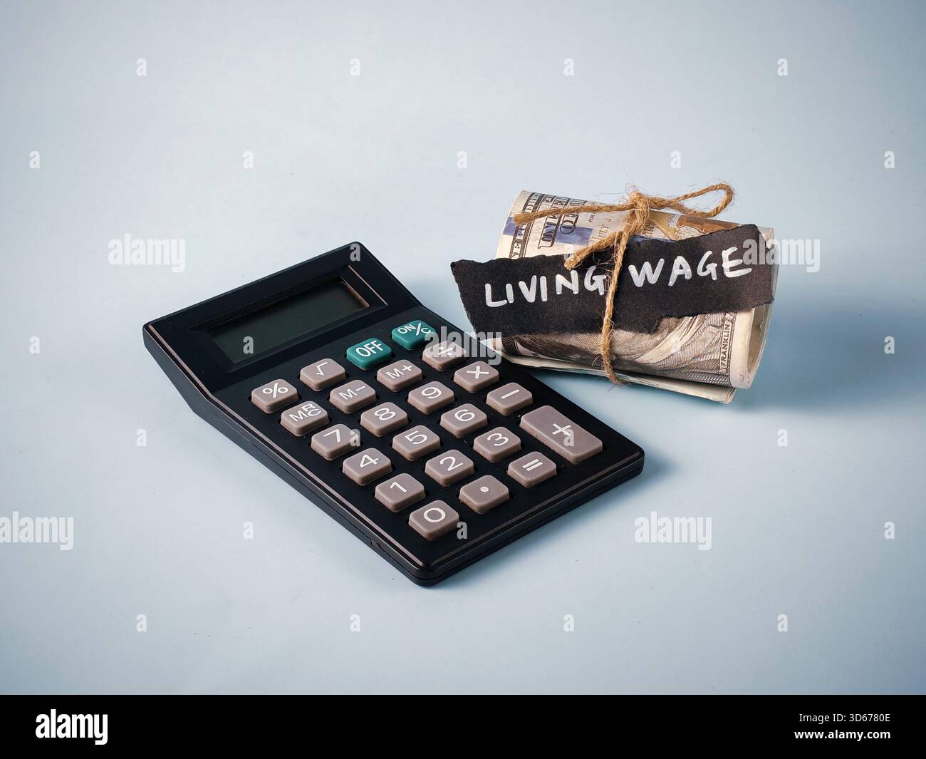 Calcolatrice e denaro arrotolato con "salario di sussistenza" testo: Concetto di calcolo del reddito minimo, budget e necessità economica Foto Stock