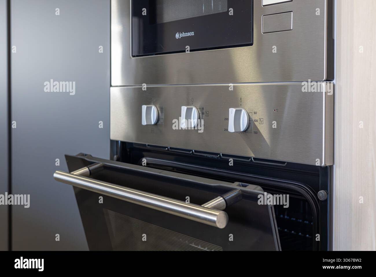 Forno elettrico in acciaio inox che mostra le manopole della temperatura e del timer nella moderna cucina Foto Stock