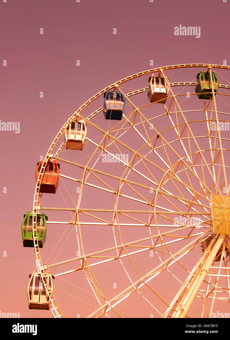 Ruota panoramica con cabine colorate che si affacciano su un cielo rosa al tramonto Foto Stock