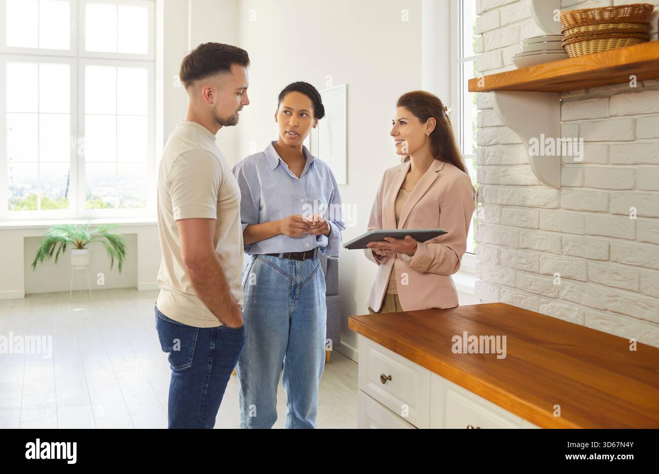 Coppia e agente immobiliare in un moderno spazio interno, visione, consulenza professionale, concentrazione Foto Stock