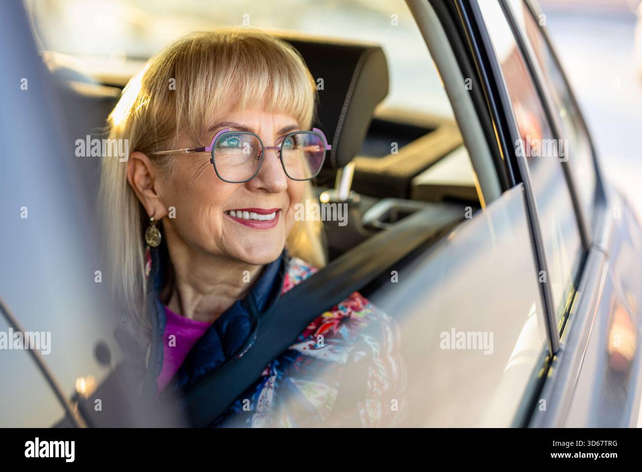 Donna anziana che guarda fuori dal finestrino dell'auto Foto Stock