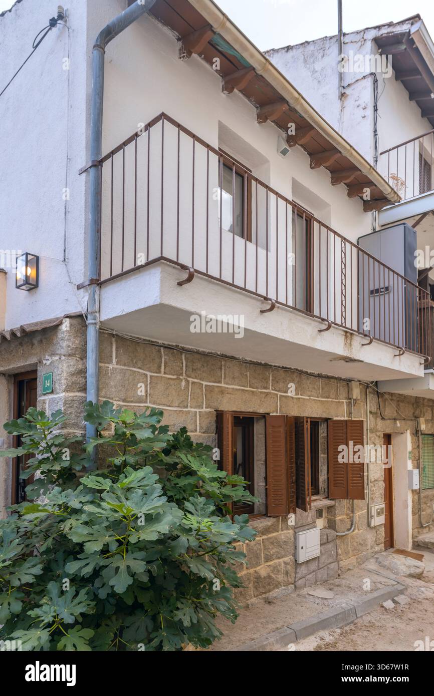 Vista laterale di una casa a schiera con un muro di granito grigio da una cava locale e persiane verdi in legno, tipiche dell'architettura vernacolare. Foto Stock