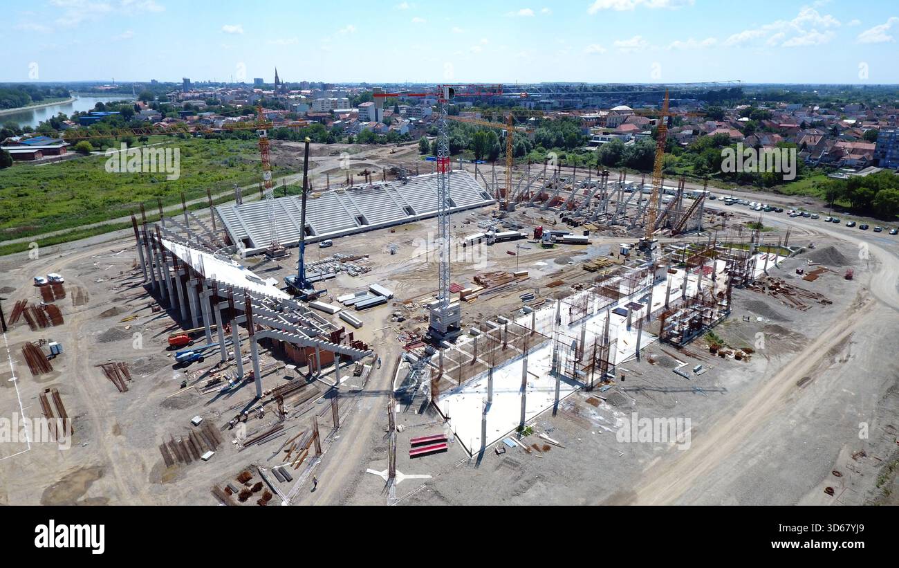 Vista aerea di uno stadio in costruzione con gru che torreggiano sopra la struttura scheletrica sullo sfondo del paesaggio urbano, Osijek, Osijek-Baranja Foto Stock