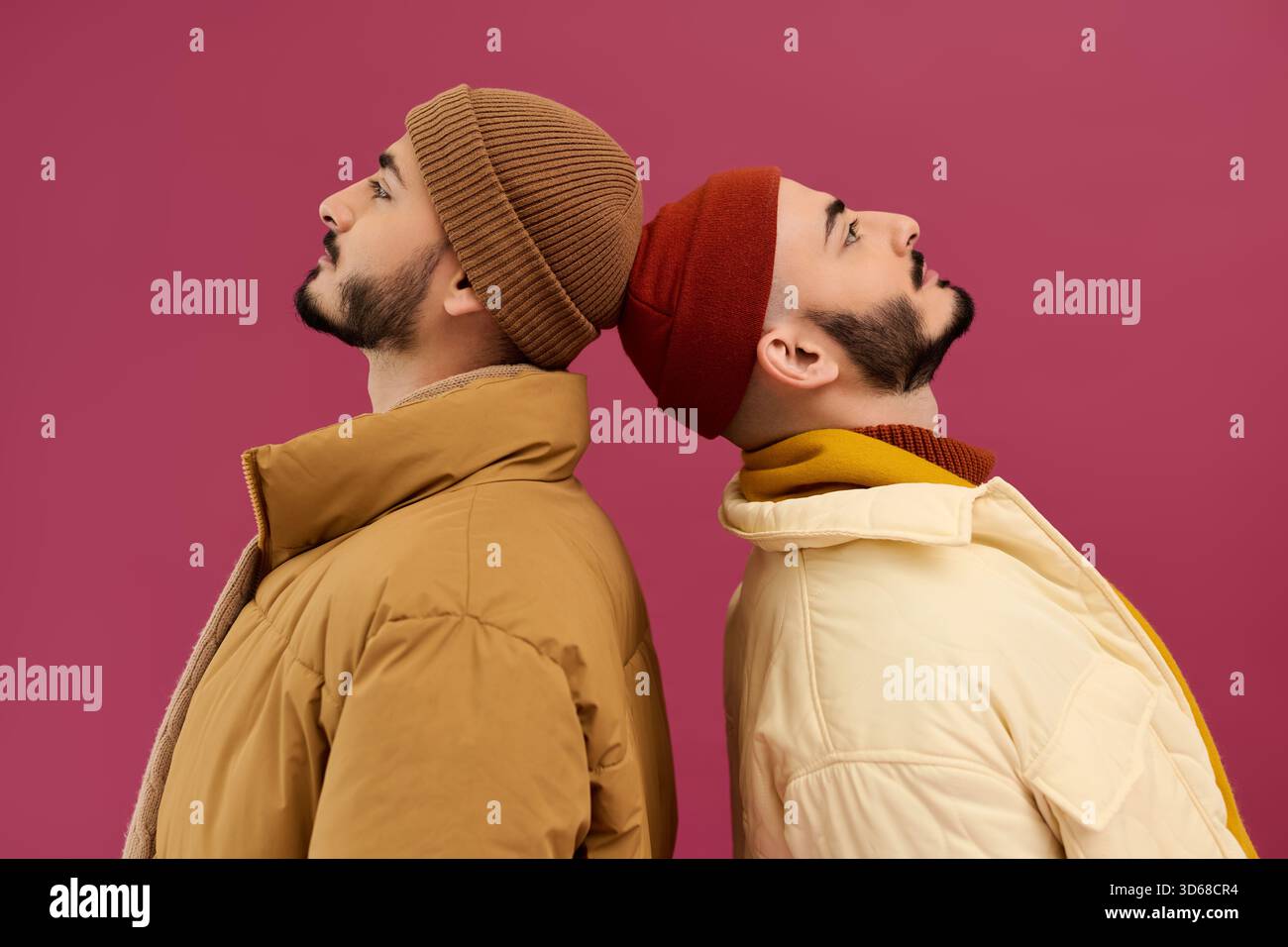 Due bellissimi fratelli in abiti alla moda si piegano a schiena, trasudando stile e sicurezza. Foto Stock
