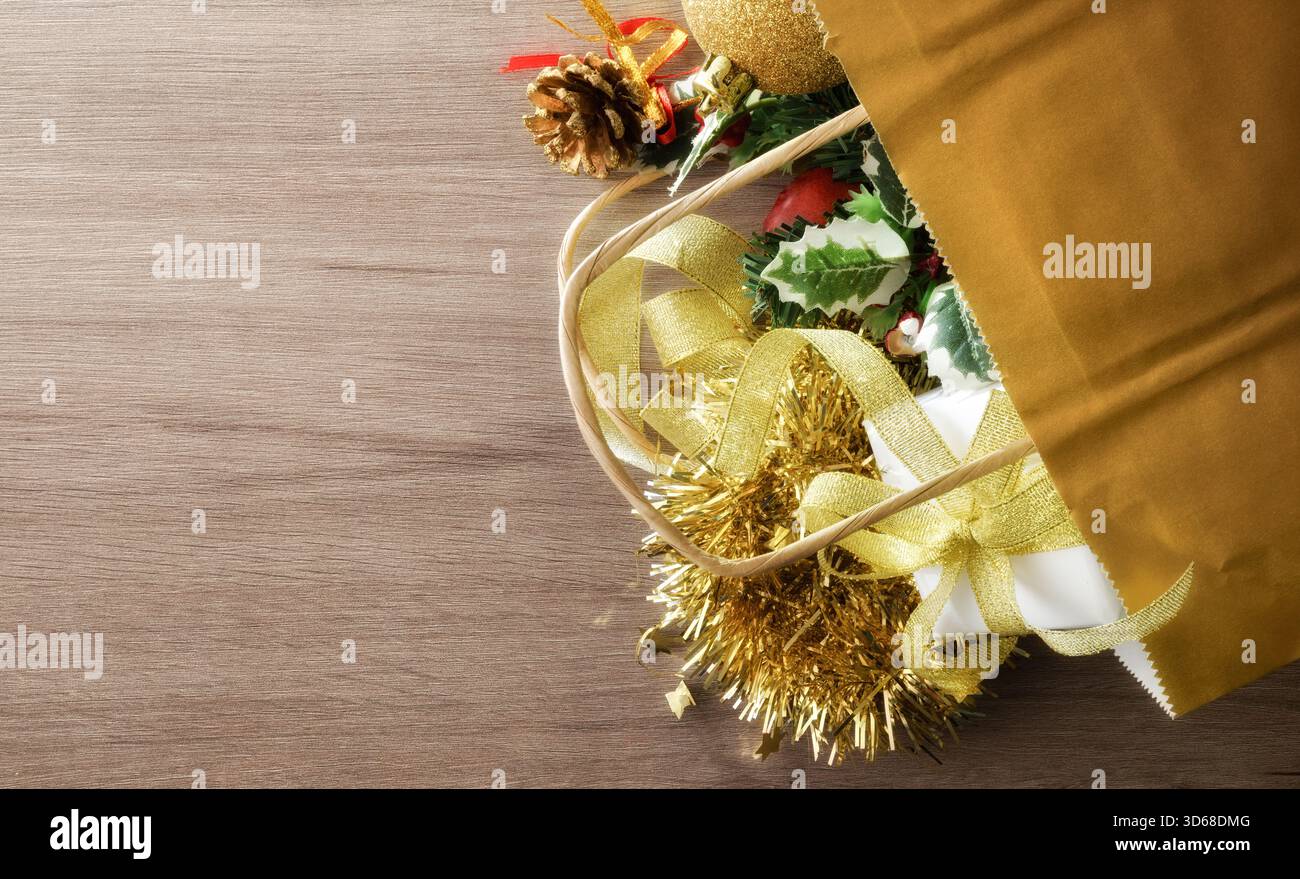 Decorazioni natalizie su una borsa della spesa dorata su un tavolo di legno. Vista dall'alto. Foto Stock