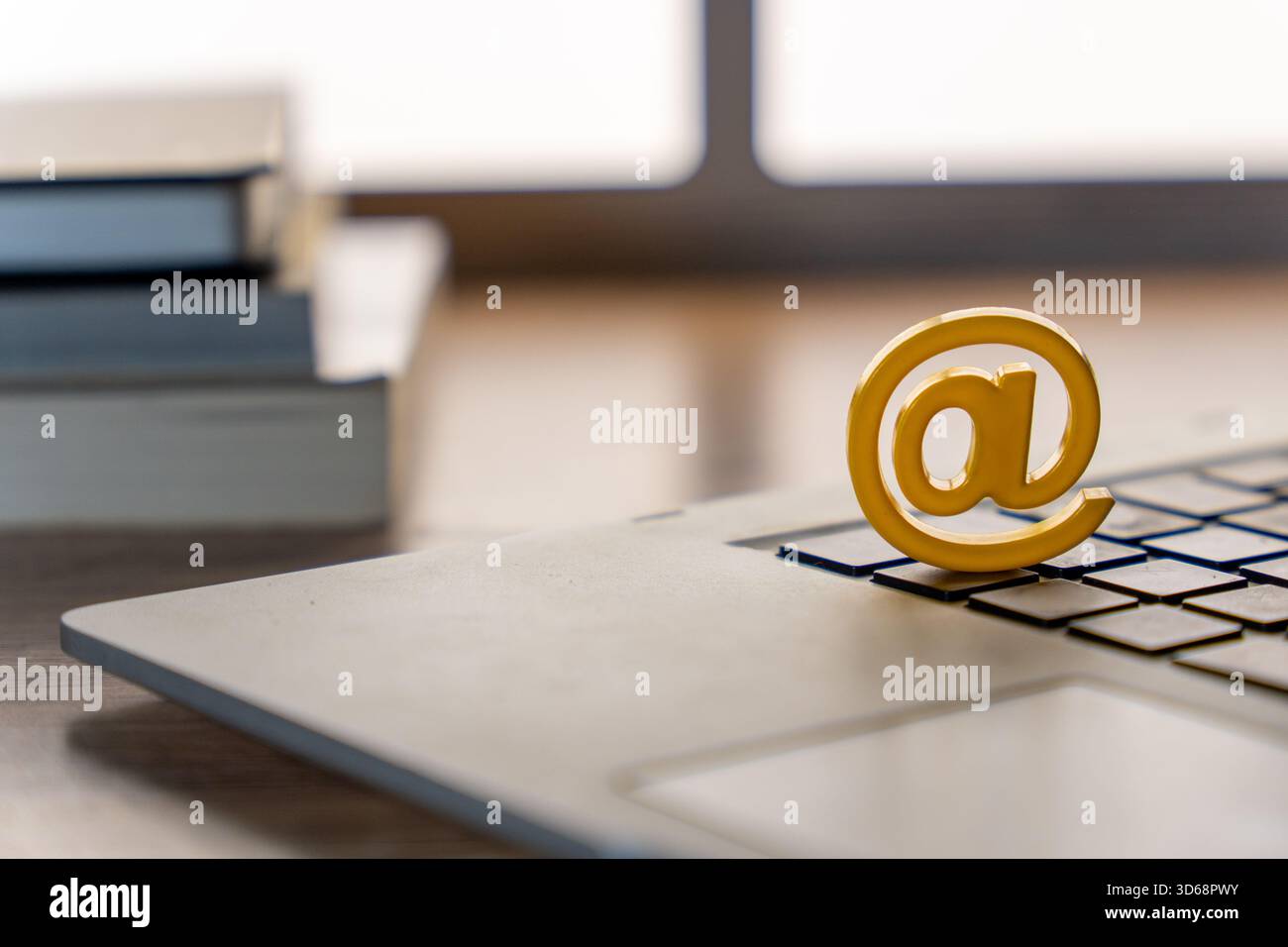 Un cartello giallo a posto sulla tastiera di un notebook con i libri impilati sullo sfondo. E-mail, comunicazione digitale, Internet, servizi online e moderno Foto Stock