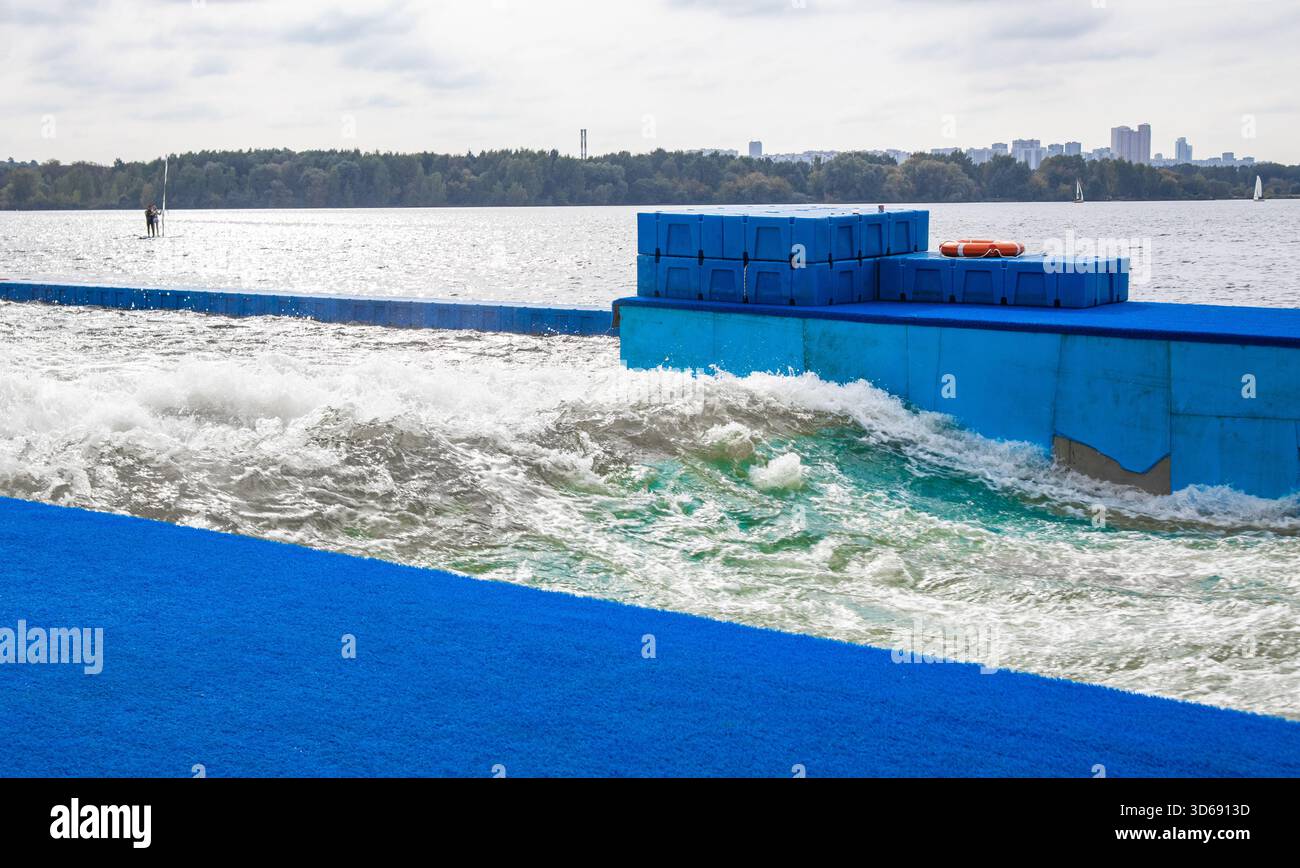 Onde di allenamento artificiale per surfisti che schiudono acqua e pontoni blu struttura sicura sul lago ideale per scuole di surf campi annunci e contenuti sullo sport A. Foto Stock