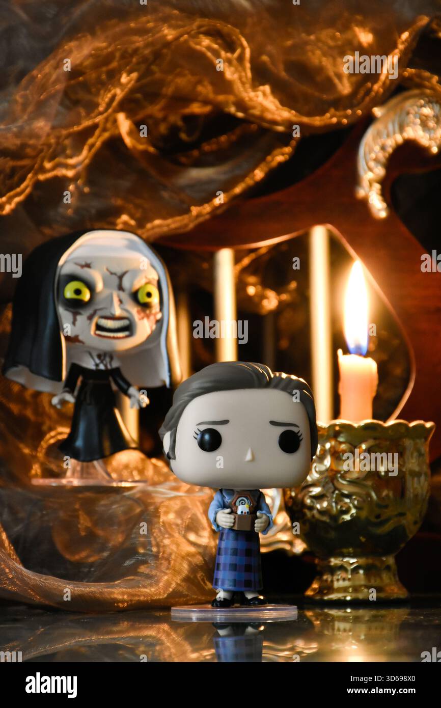 Funko Pop action figure di Lorraine Warren e la suora del film horror Conjuring. Antico tempio buio, la candela accesa brucia nel semi-buio. Foto Stock