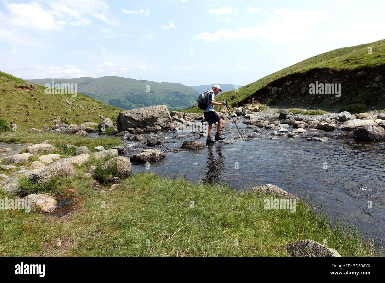 Lone Man (escursionista) camminando sull'Outflow fino a Easedale Tarn dalla Wainwright 'Tarn Crag' vicino a Grasmere, Lake District, Cumbria, Inghilterra, Regno Unito. Foto Stock