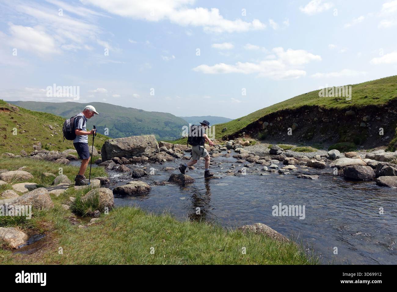 Due uomini (escursionisti) camminando sull'Outflow fino a Easedale Tarn dalla Wainwright 'Tarn Crag' vicino a Grasmere, Lake District, Cumbria, Inghilterra, Regno Unito. Foto Stock