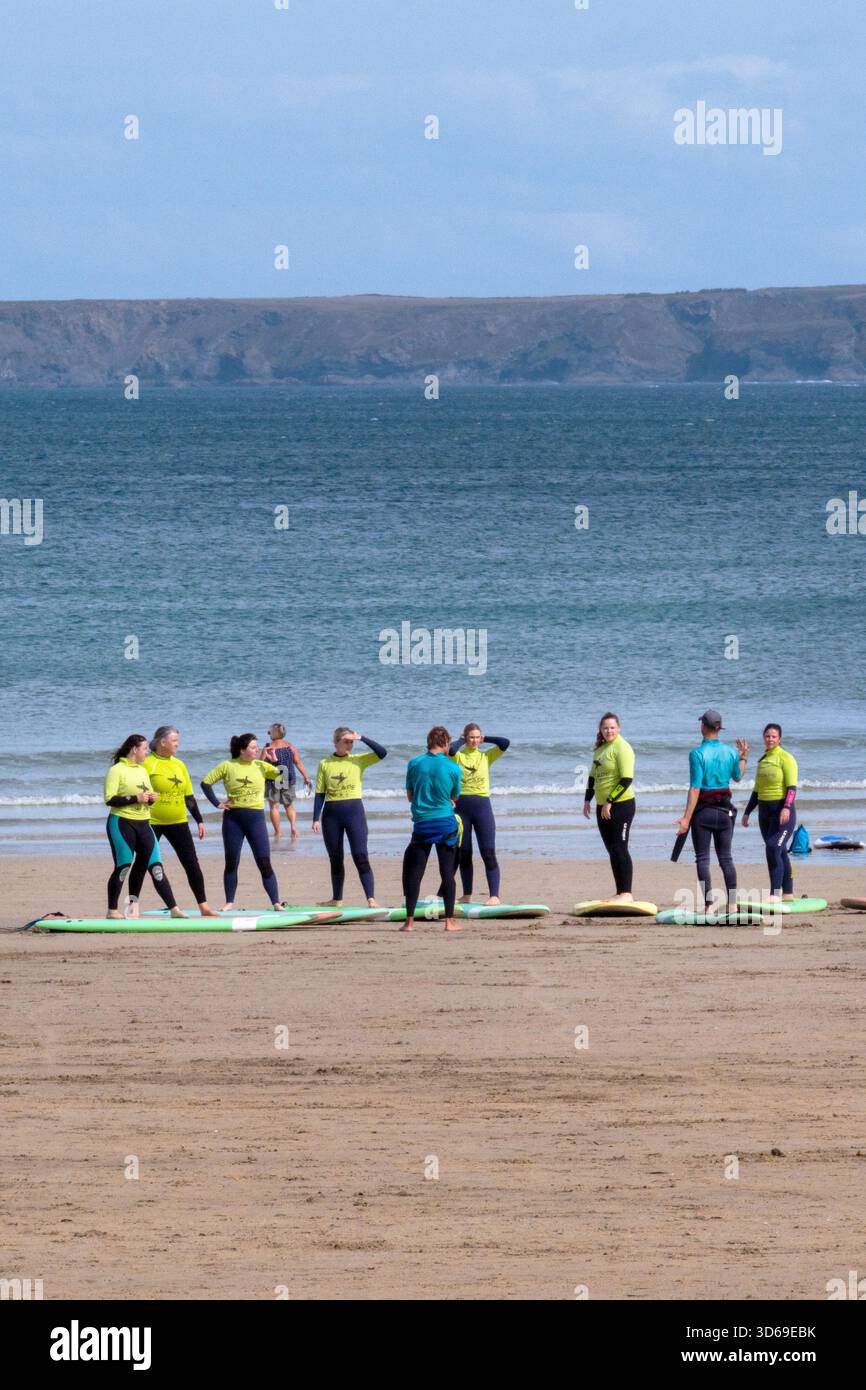 Persone che partecipano a una lezione di surf condotta da istruttori della Escape Surf School di Towan Beach a Newquay, in Cornovaglia, in Inghilterra, nel Regno Unito. Foto Stock