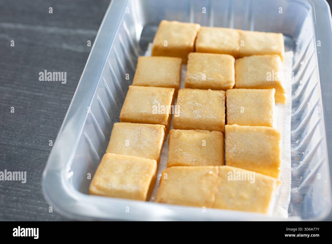 Una vista di un contenitore di plastica di quadrati di tofu di pesce. Foto Stock