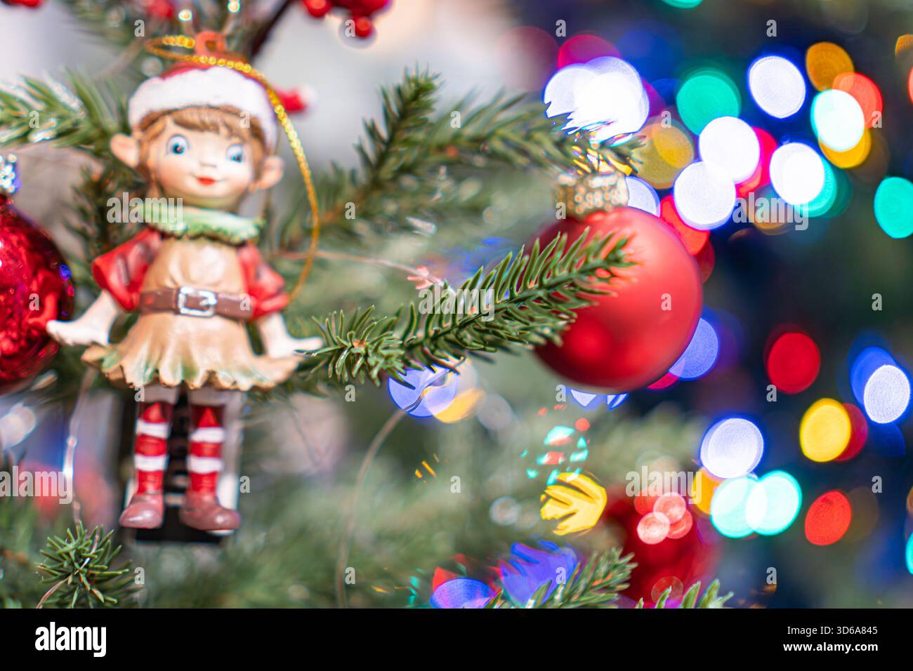 Una scena festosa con un albero di Natale decorato, caratterizzato da una vivace statuina per bambini in cima a una base di pupazzi di neve, l'albero è decorato con diversi ornamenti Foto Stock