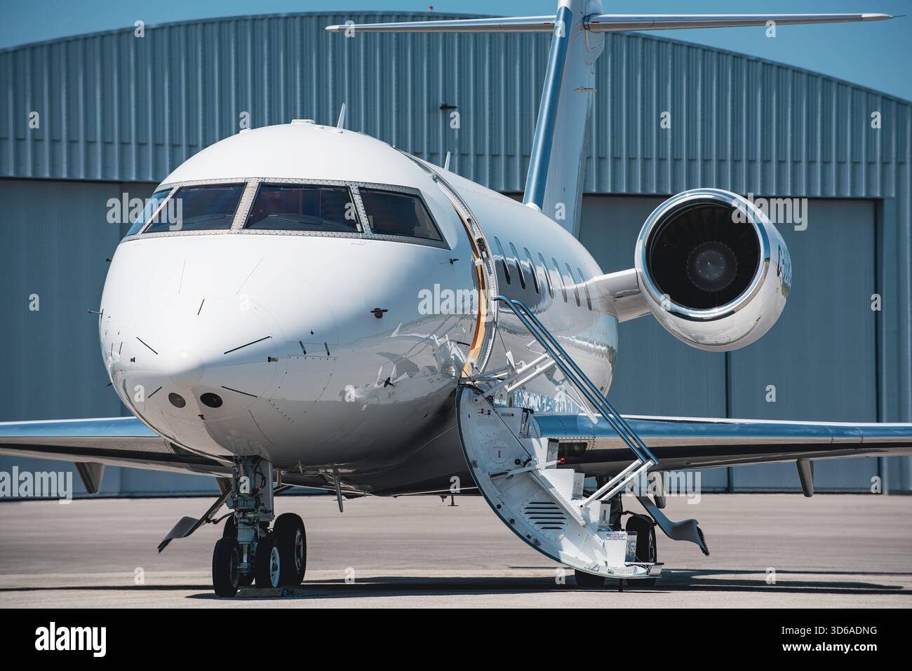 Vista frontale di tre quarti dei moderni aerei business jet bianchi con le scale d'imbarco estese. Foto Stock