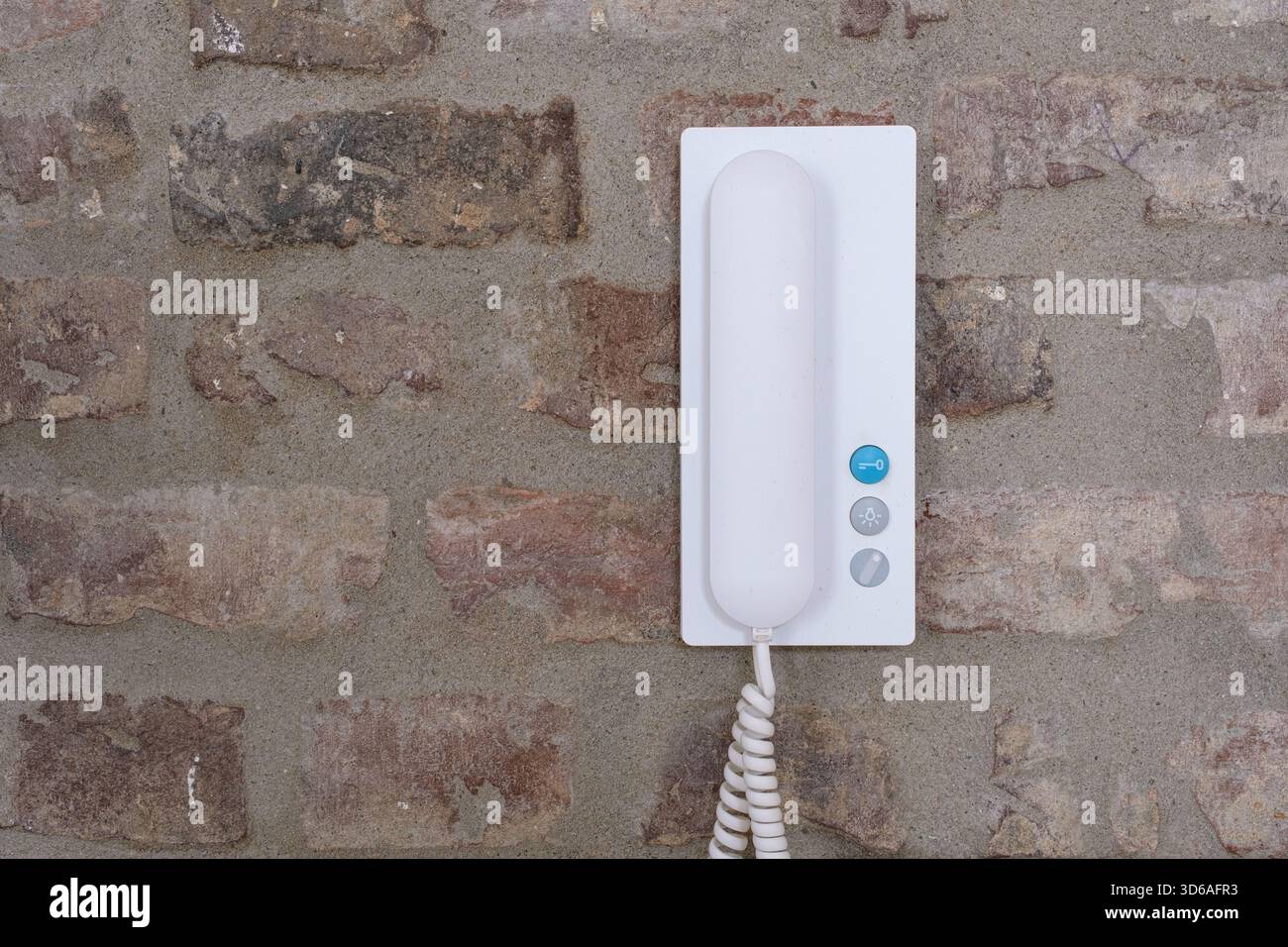 Telefono interfono bianco montato a parete su una parete rustica in mattoni Foto Stock