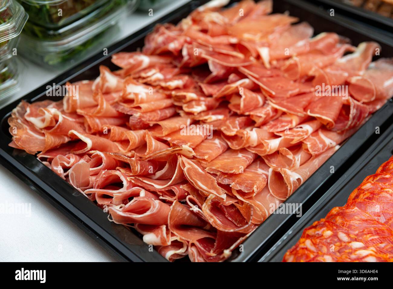 Vista ravvicinata di un piatto di salumi ben organizzato con affettati sottili. ideale per presentazioni gastronomiche o eventi culinari. Foto Stock
