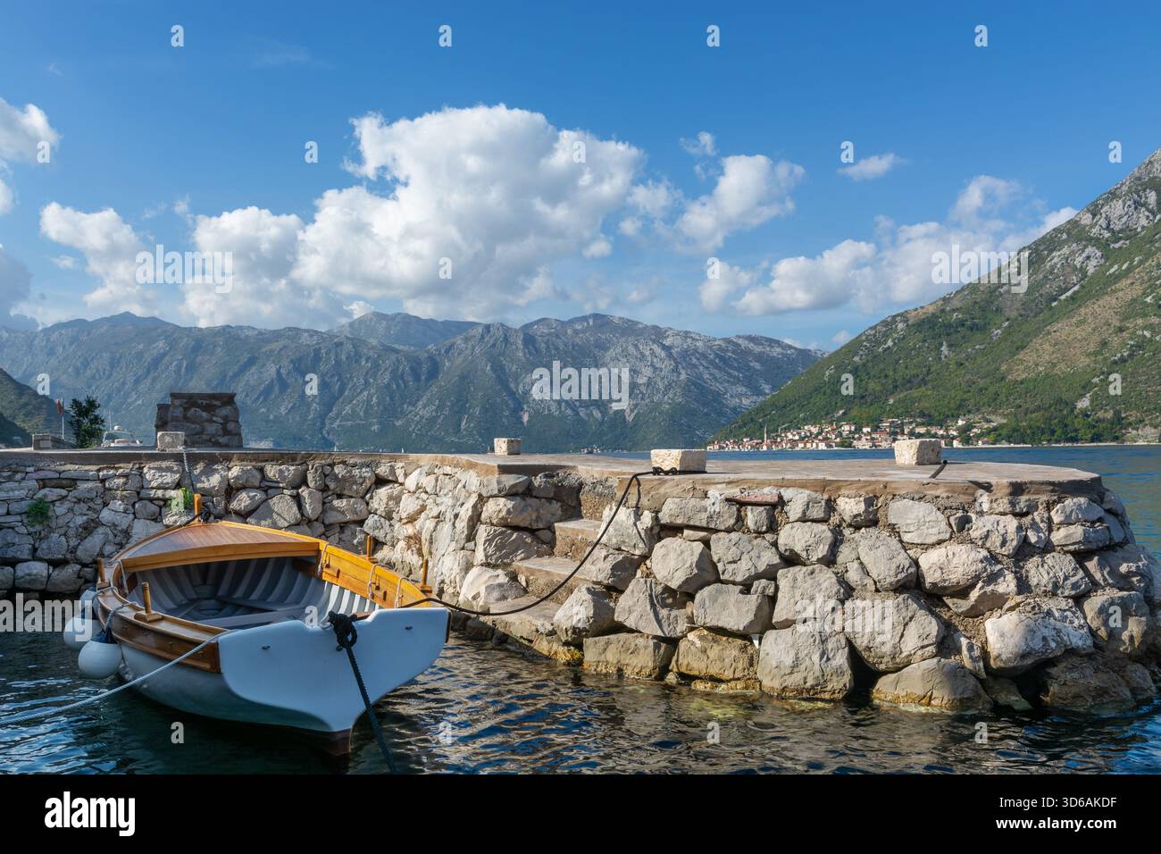 Tradizionale peschereccio in legno ormeggiato in pietra «mulo» (piccoli bacini per barche da pesca), affacciato in lontananza sulla baia di Cattaro e sulla città di Perast. Foto Stock
