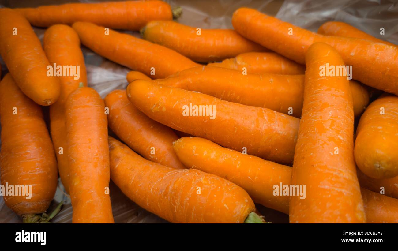 Primo piano di carote d'arancia fresche con superficie naturale in un mucchio. Foto Stock
