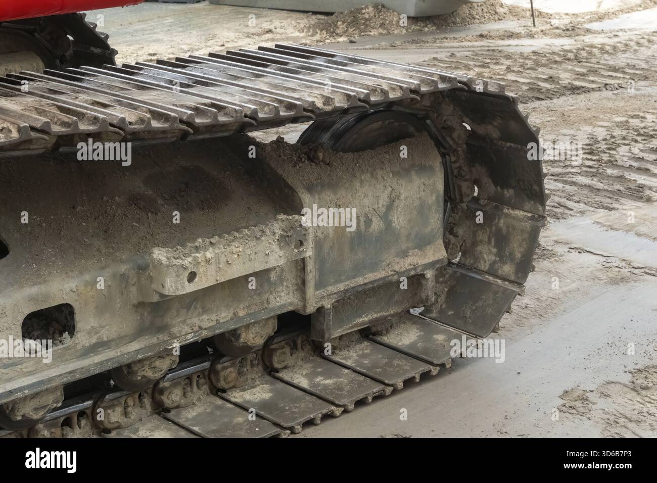 Borken, NRW, Germania, vista ravvicinata dei cingoli fangosi su macchinari edili pesanti in cantiere. Segni di usura e sporcizia evidenziano la sfida Foto Stock