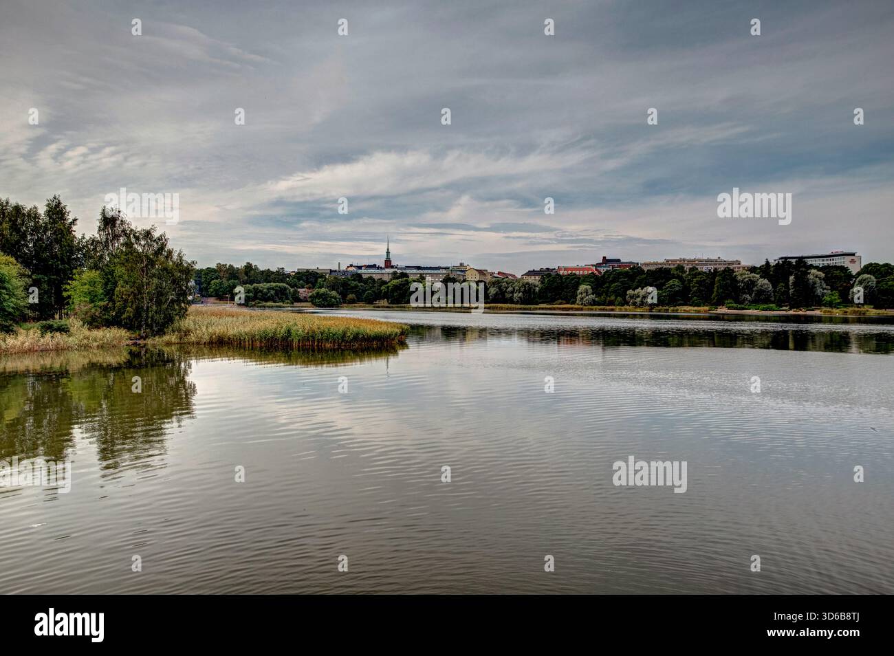 Riflessi allo stagno Tammilampi di Helsinki con la facciata in marmo bianco della Finlandia Hall (dell'architetto Alvar Aalto) visibile oltre le canne. Foto Stock