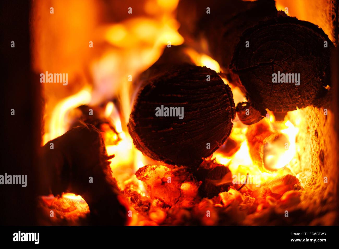 Legna da ardere nel caminetto. Primo piano di tronchi in fiamme in un caminetto, calde fiamme arancioni e braci accese: Caldo caldo e atmosfera invernale. Foto Stock