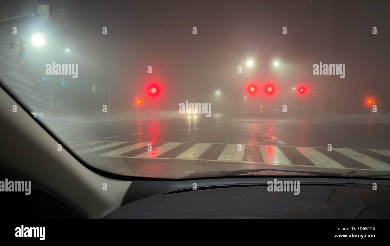 Intersezione stradale nelle notti piovose visto dal punto di vista del conducente Foto Stock