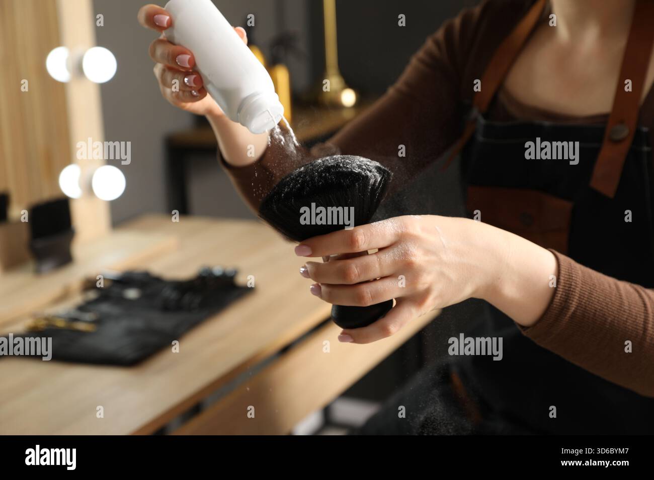 Parrucchiere che mette polvere di talco sulla spazzola al salone, primo piano Foto Stock