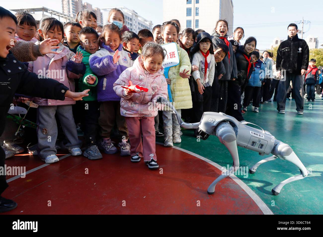 Gli studenti delle scuole elementari interagiscono con un cane robotico nella città di Huai'an, provincia di Jiangsu, Cina, il 20 novembre 2025. Foto Stock