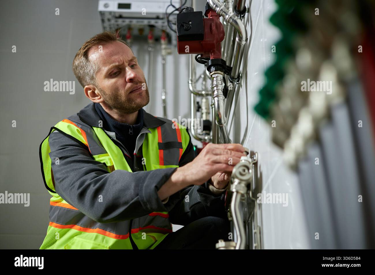 Uomo caucasico di mezza età che ispeziona le apparecchiature del sistema di riscaldamento industriale Foto Stock