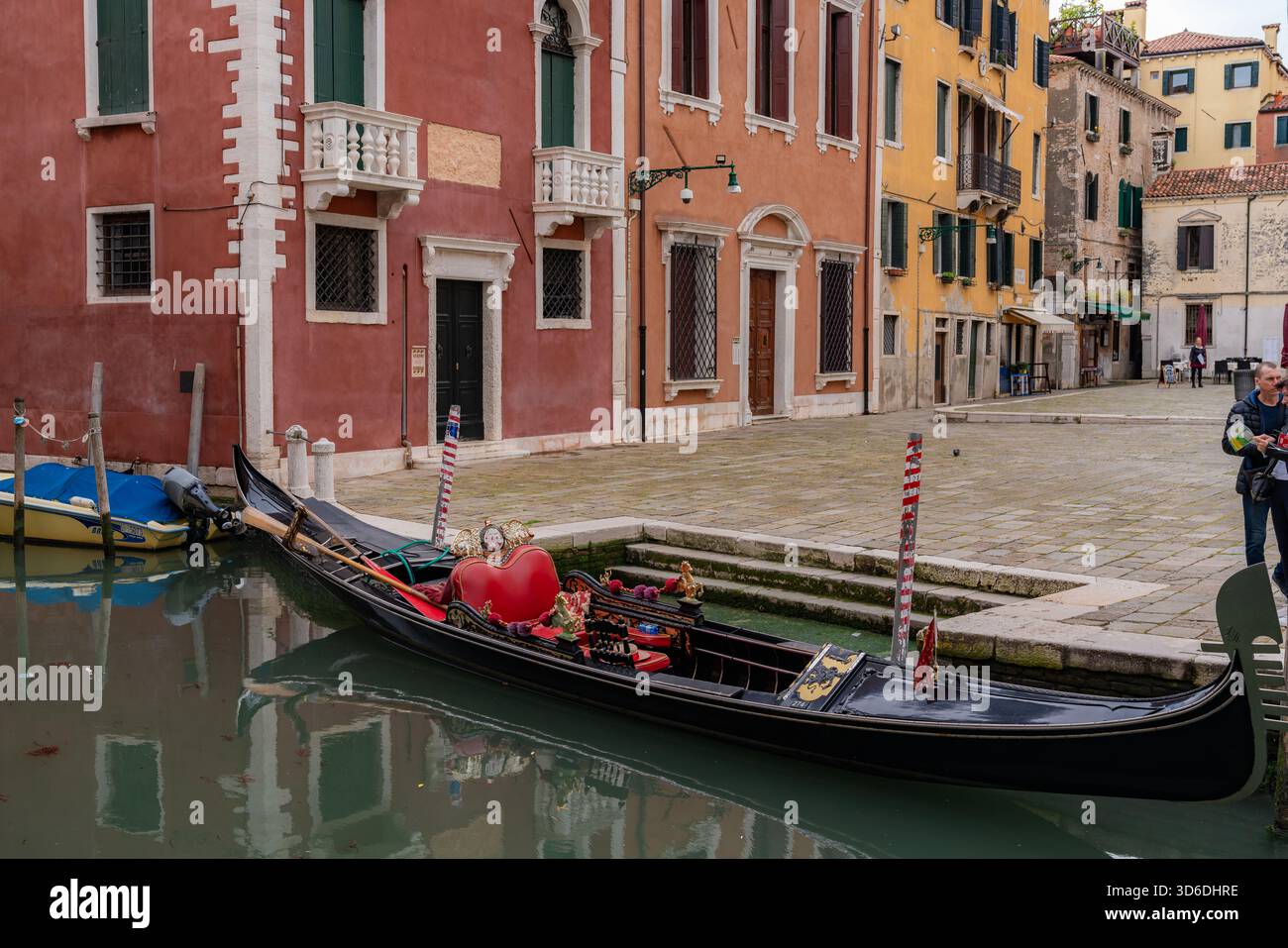 Vista romantica di un canale veneziano con una gondola che scivola tra edifici storici, riflessi d'acqua calmi che creano un'atmosfera senza tempo Foto Stock
