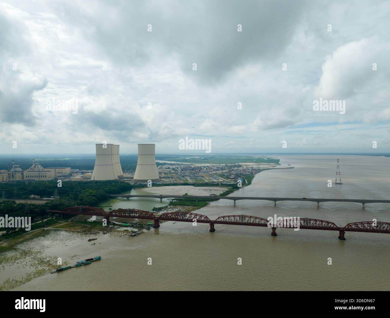 Veduta aerea dei torreggianti reattori nucleari e di un lungo ponte su un ampio fiume sotto un cielo nuvoloso, Ruppur, divisione Rajshahi, Bangladesh. Foto Stock