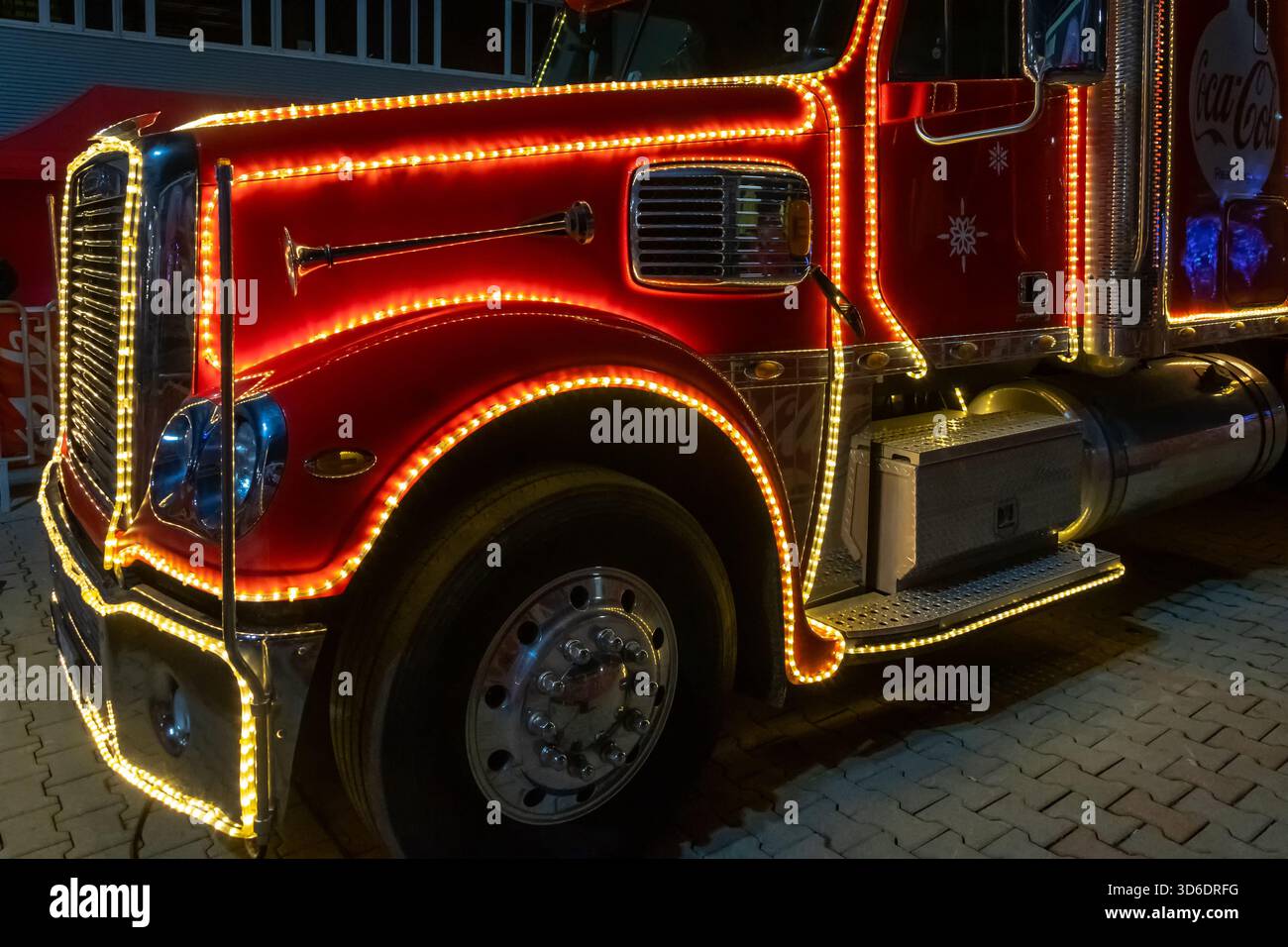 La ruota e la parte anteriore di un camion Coca-Cola sono illuminate con luci natalizie, Austria, Vienna, 13 dicembre 2024 Foto Stock