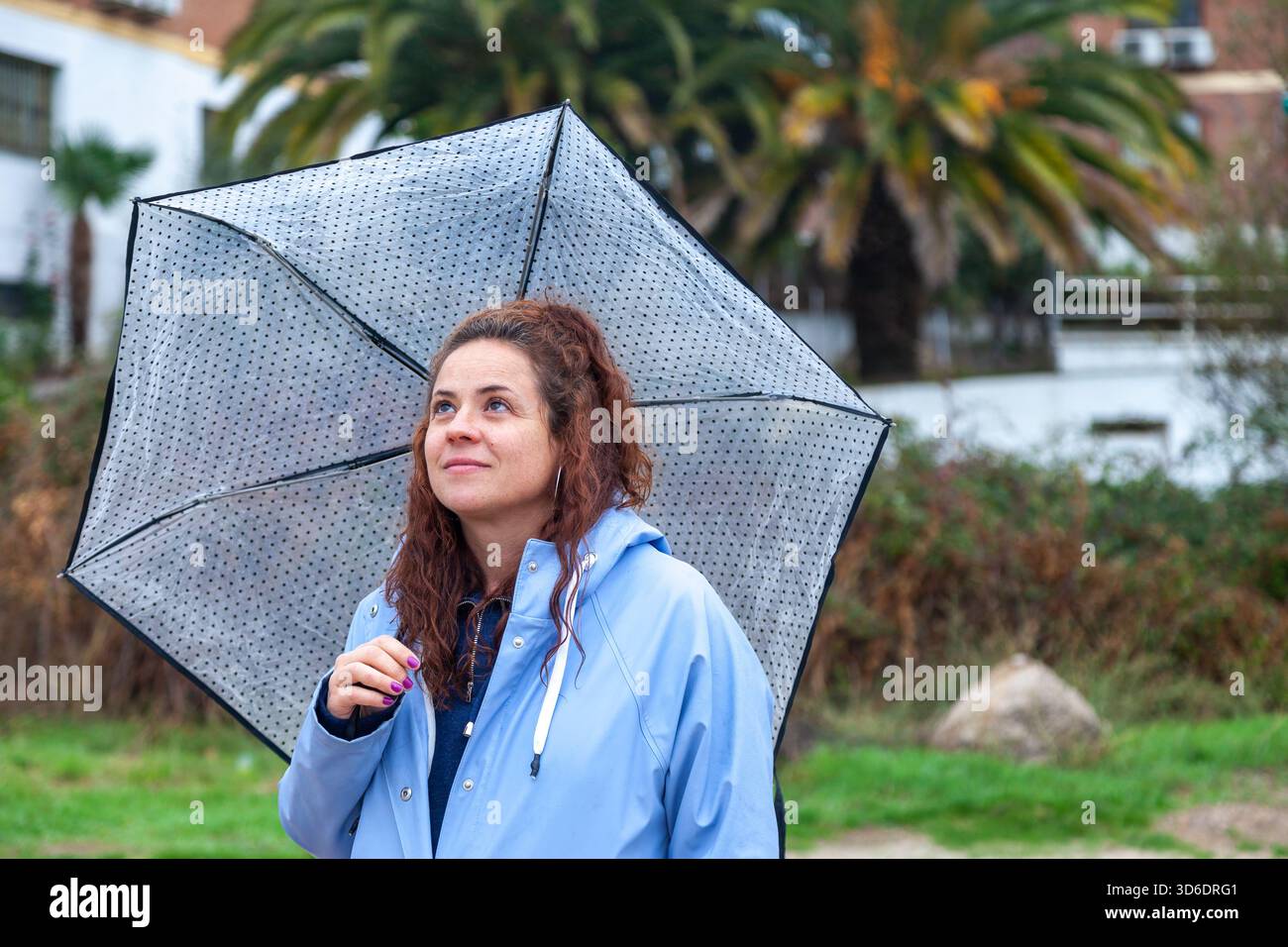 Candid Lifestyle Scene di donna in impermeabile blu con tempo piovoso Foto Stock