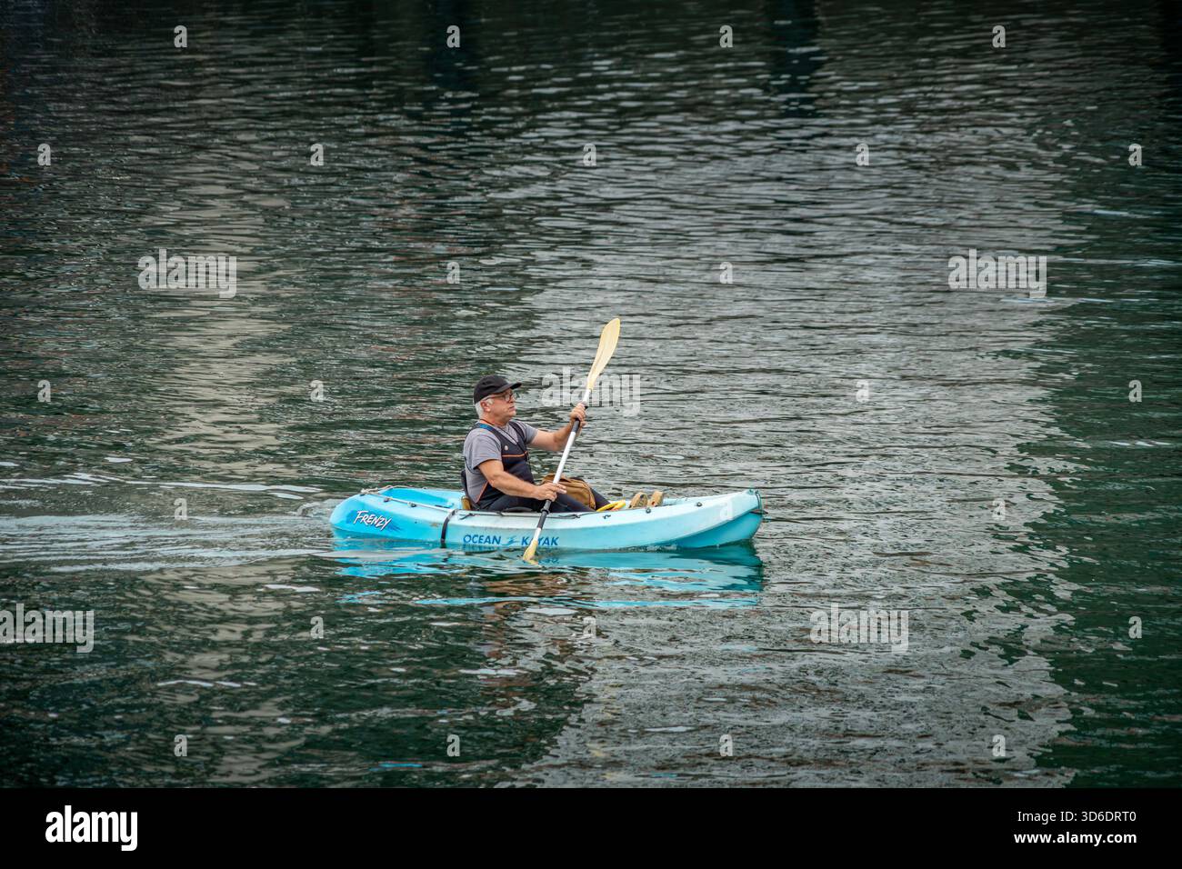 Uomo che pagaia in kayak azzurro sull'acqua calma, attività ricreative estive, stile di vita attivo, sport per il tempo libero, orizzontale Foto Stock