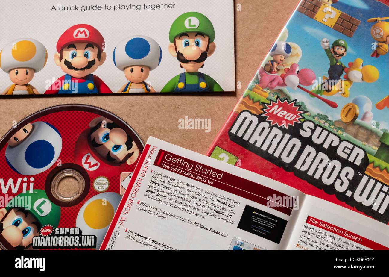 "Nuovo disco Nintendo Wii Super Mario Bros" con copertina e libretto di istruzioni, isolato su sfondo liscio chiaro, angolo superiore Foto Stock