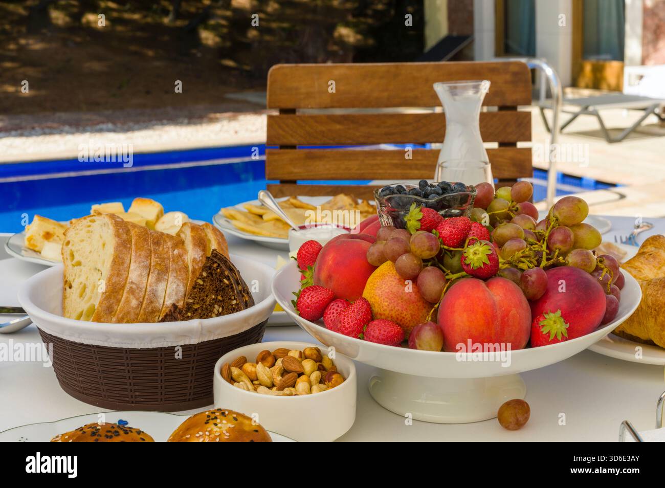 un tavolo per la colazione con bevande e frutta vicino a una piscina, shot all'aperto Foto Stock