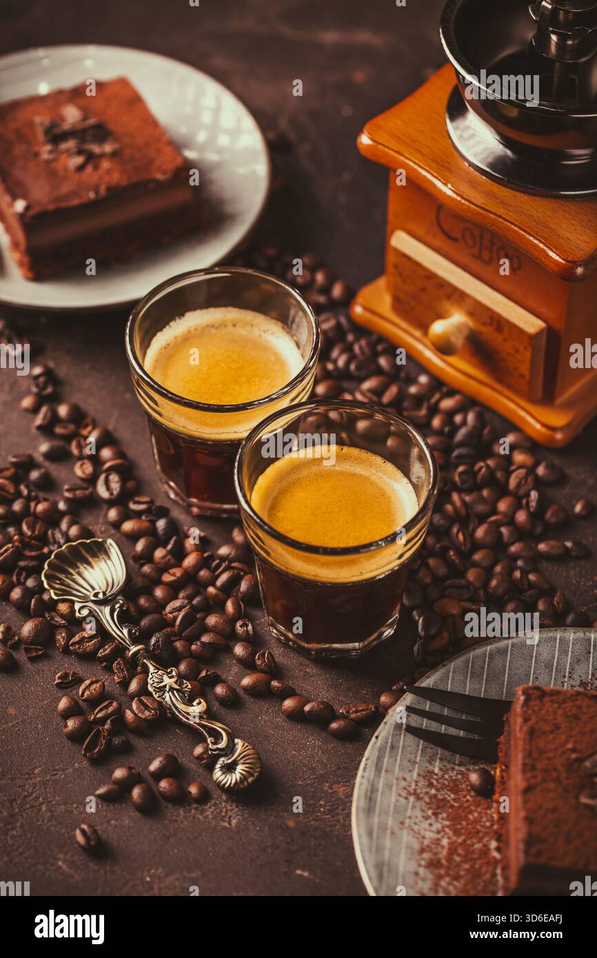 Due tazze da caffè espresso con una fetta di torta al cioccolato su sfondo marrone Foto Stock