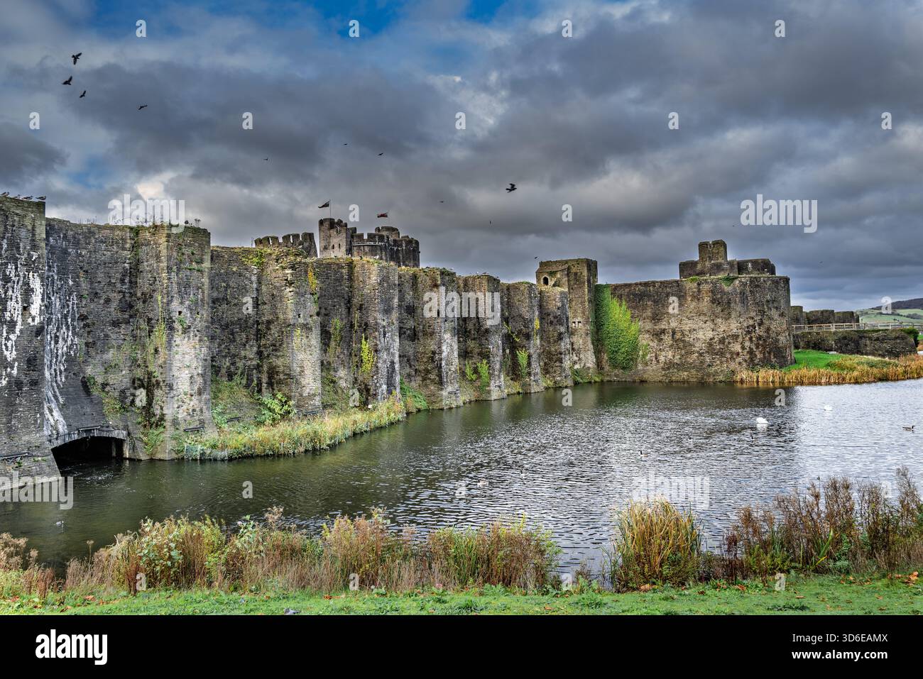 Una vista suggestiva del Castello di Caerphilly, le sue enormi mura di pietra e torri che si innalzano sopra il fossato ancora nel cuore del Galles del Sud. Foto Stock