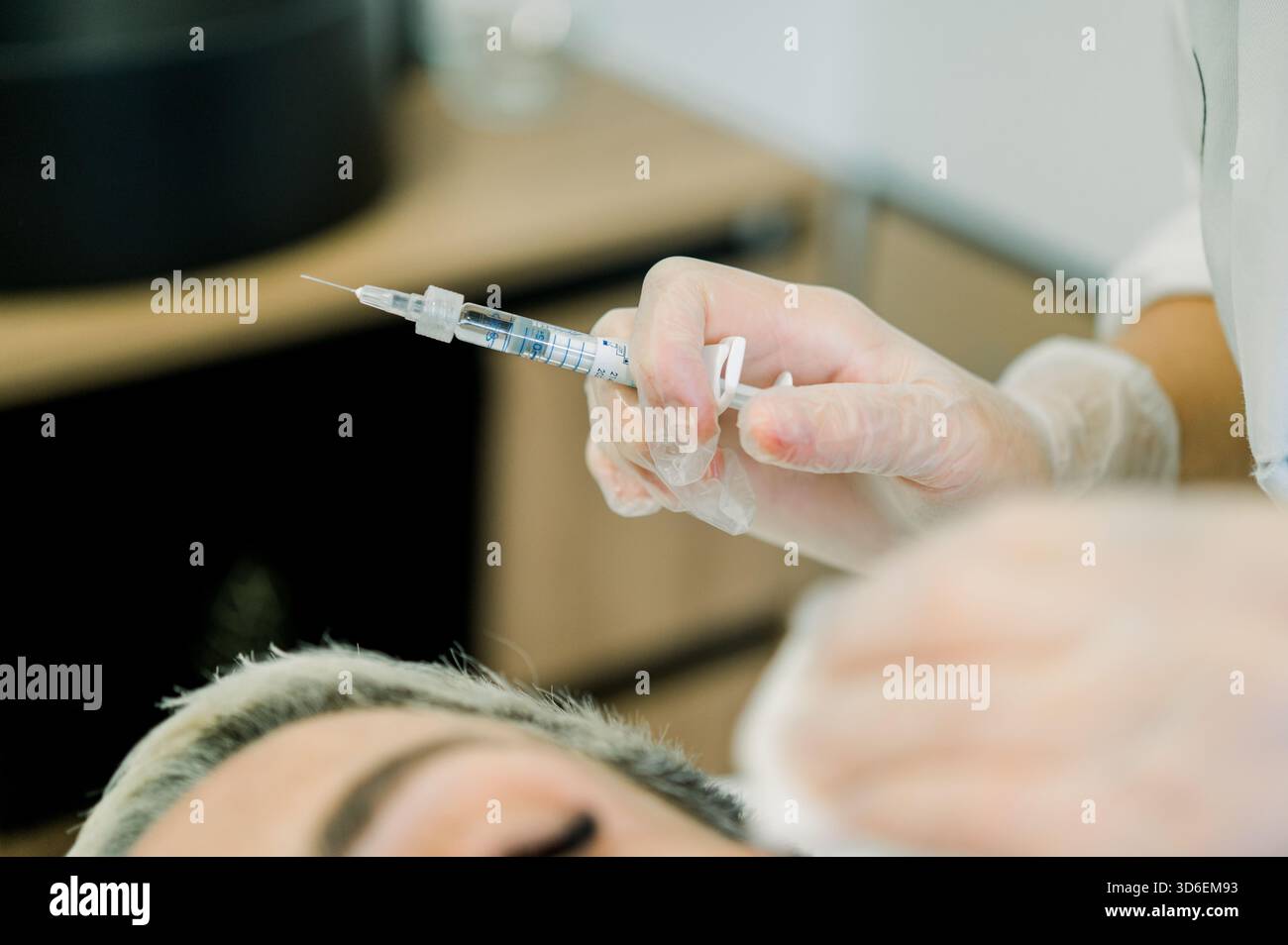 Un operatore sanitario prepara un'iniezione per un trattamento cosmetico, fornendo acido ialuronico, botox, o terapia del filo tensore in un cl estetico Foto Stock