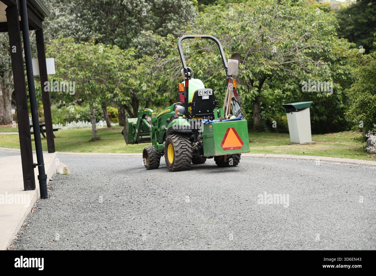 Il trattore compatto verde guida lungo un percorso curvo Foto Stock