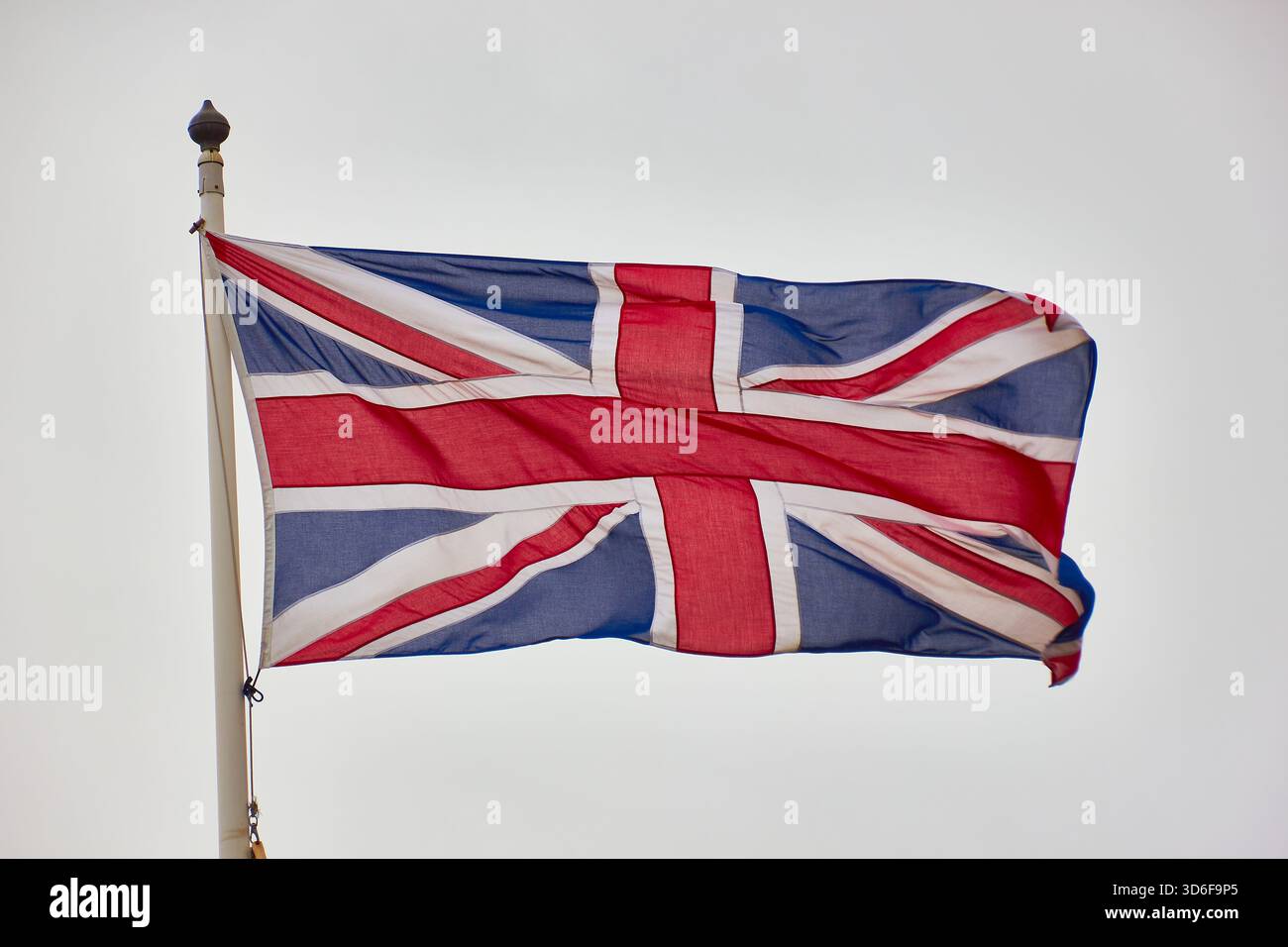 Bandiera Union Jack in volo sul palo contro Bright Sky, simbolo della Gran Bretagna e orgoglio Foto Stock