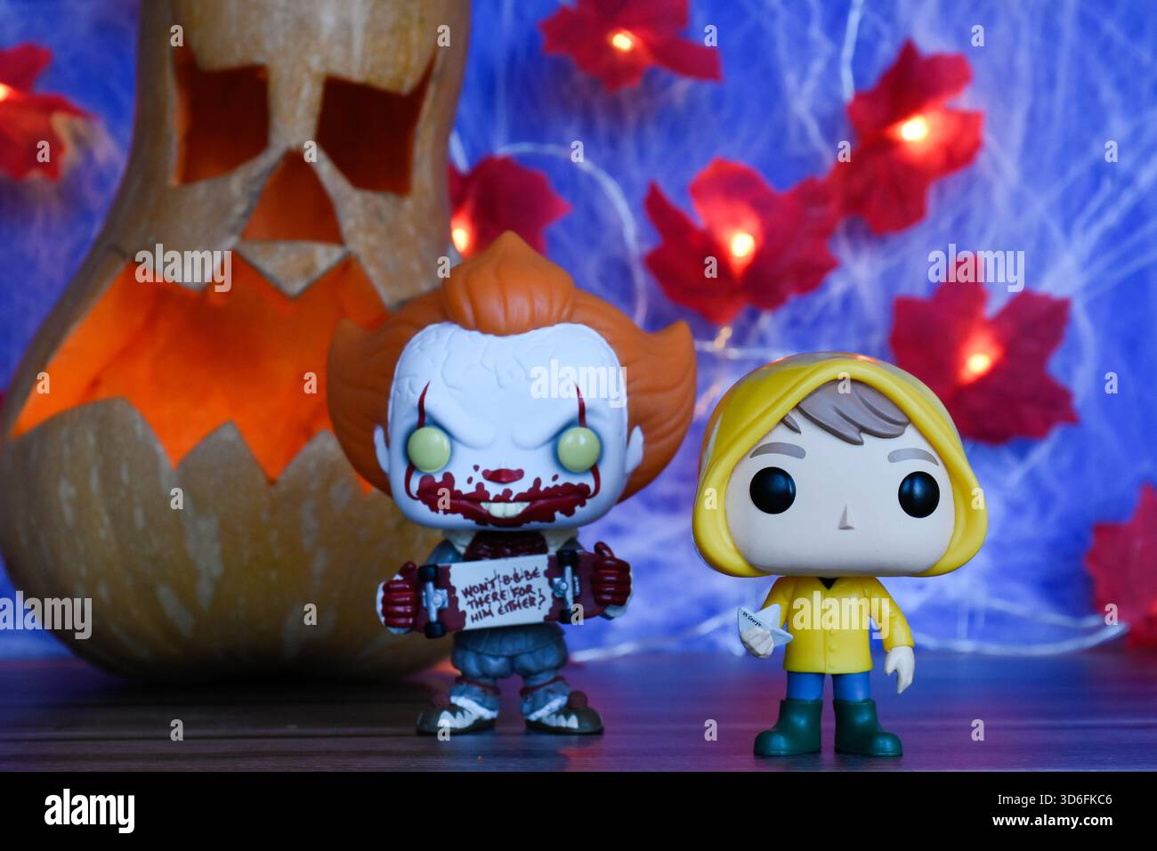 Funko Pop action figure di clown Pennywise e Georgie del film horror IT. Arredamento di Halloween, Jack o lanterna, ragnatela, foglie, luci. Foto Stock