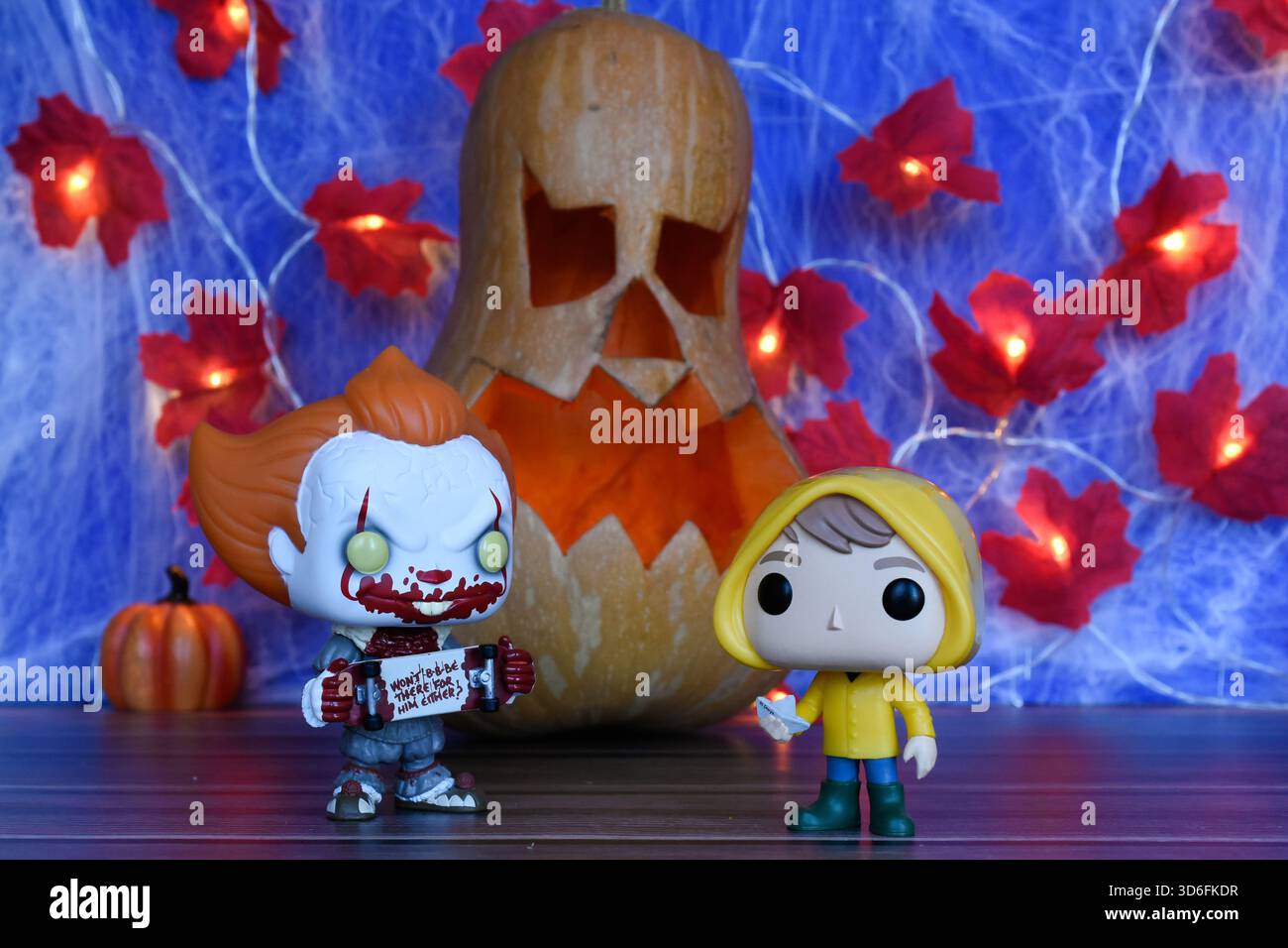 Funko Pop action figure di clown Pennywise e Georgie del film horror IT. Arredamento di Halloween, Jack o lanterna, ragnatela, foglie, luci. Foto Stock