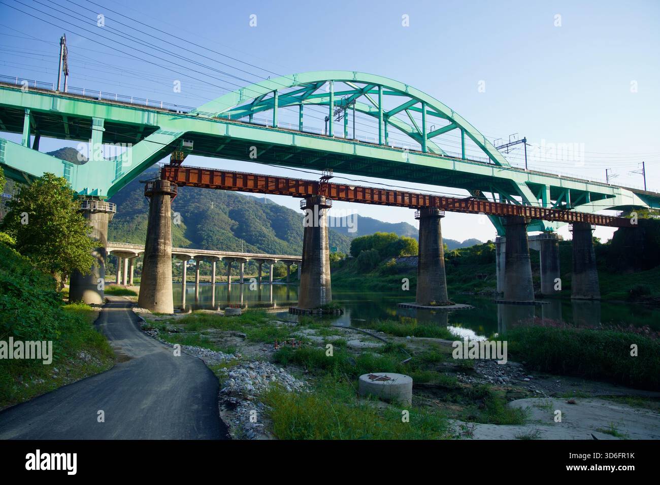 Sotto l'arco color acquamarina del ponte della linea Gyeongchun a Cheongpyeong, un'antica estensione rotaia color ruggine e distanti viadotti si sovrappongono attraverso il Bukhan Foto Stock